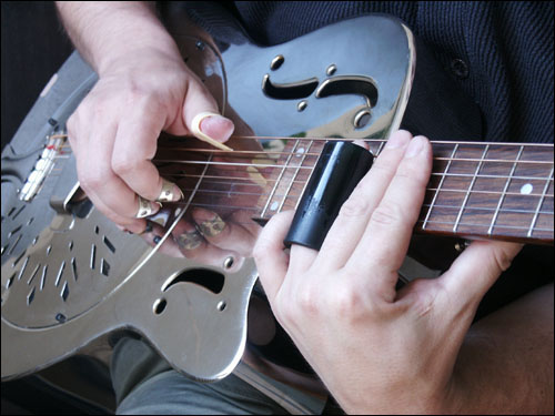 Example of a bottleneck slide, with fingerpicks and a resonator guitar made of metal