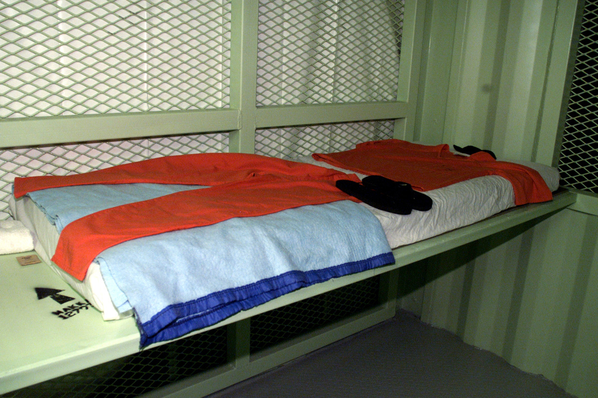 Comfort items issued to detainees at Camp Delta, Guantanamo Bay, Cuba, include: a copy of the Koran, a mattress, sheet, blanket, prayer mat, two-piece suit, flip-flop shoes, prayer cap, wash cloth and towel, and a salt packet for seasoning food. Note the arrow pointing to Mecca