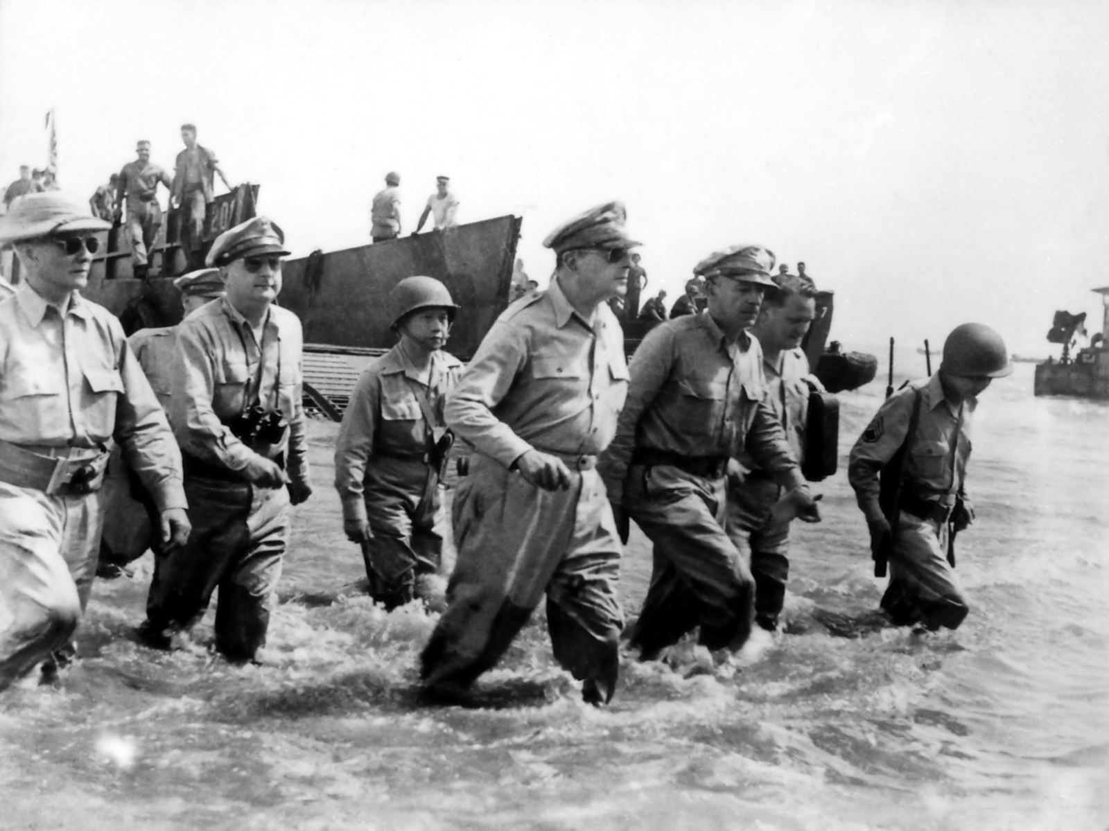 "I have returned" — General MacArthur returns to the Philippines.|alt=Seven men in uniform wade through the surf.