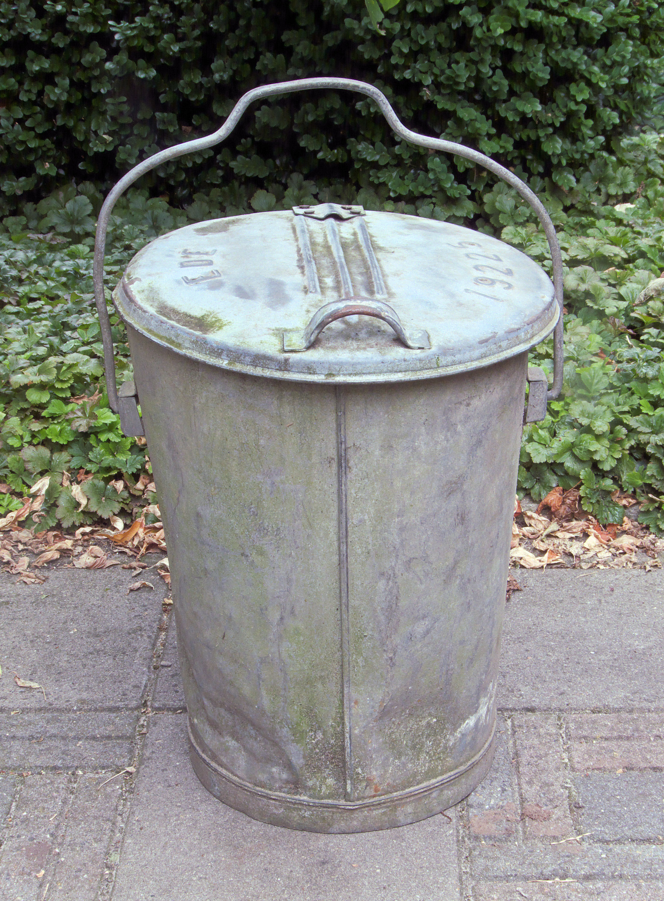 A galvanized steel trash can of the type manufactured by Behrens