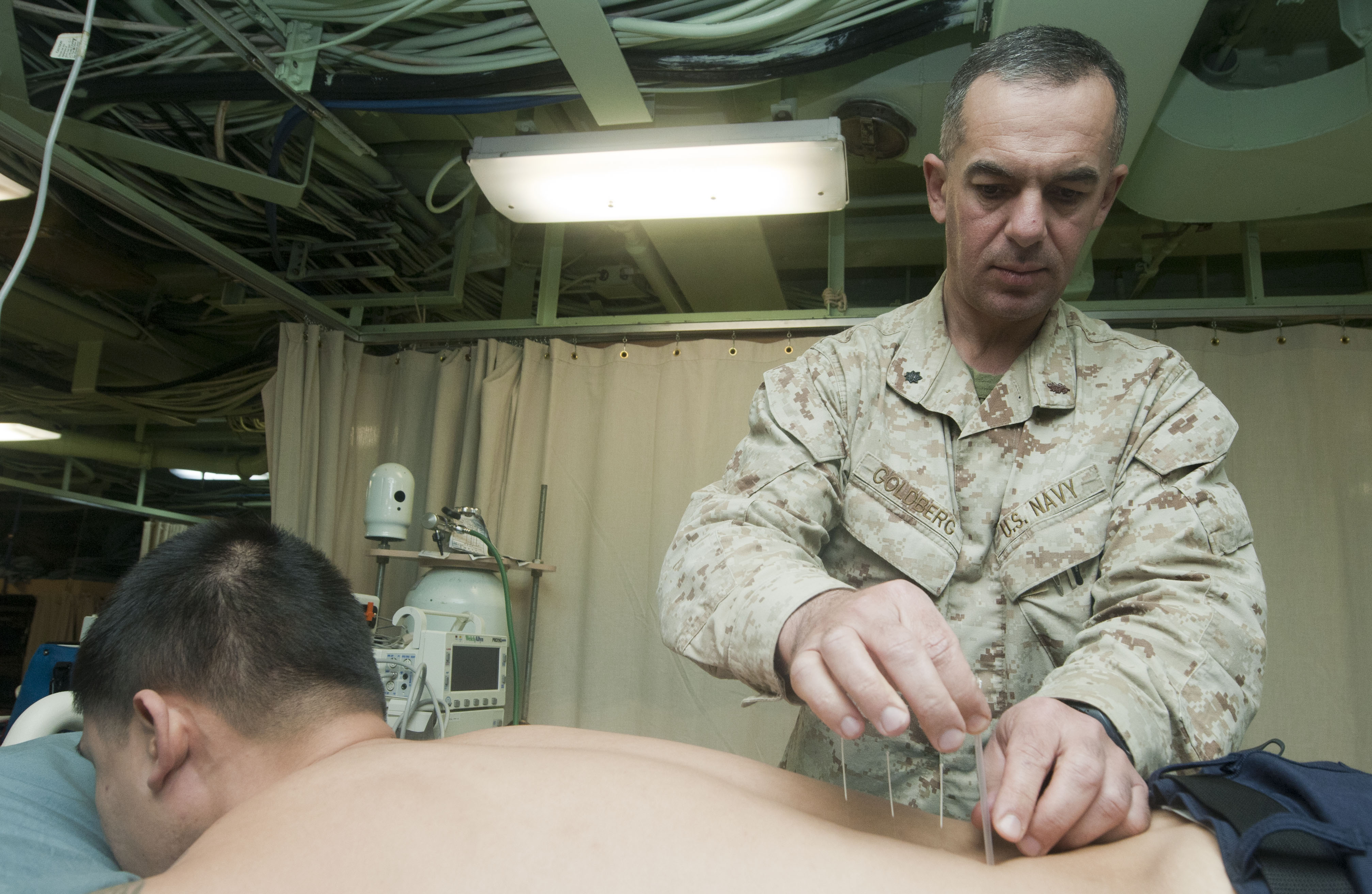 An officer assigned to the 11th Marine Expeditionary Unit of the U.S. Navy performs acupuncture aboard the USS New Orleans 